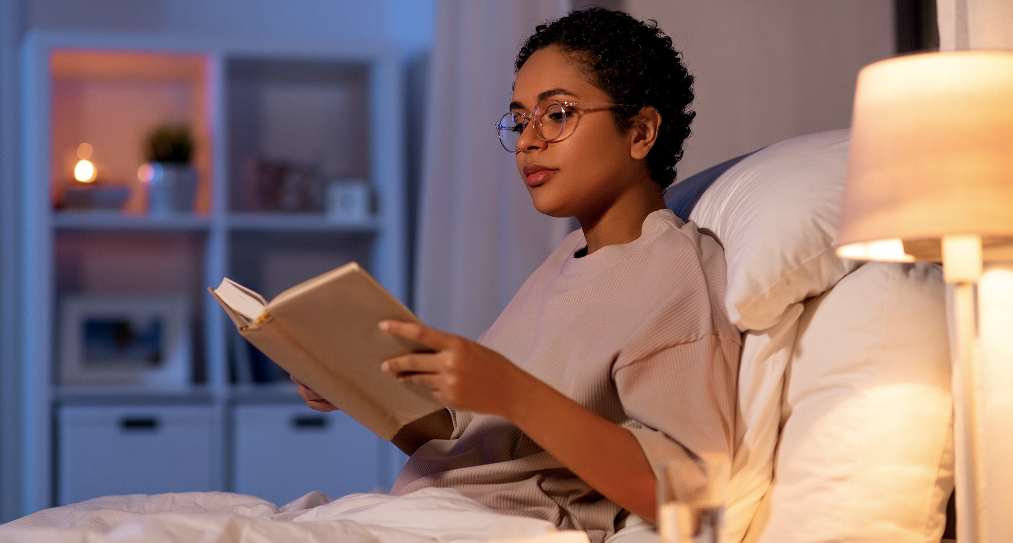 persoon die een bril draagt en een boek leest in een zwak verlichte kamer